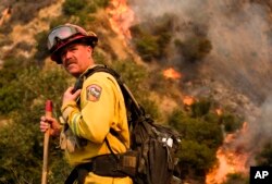 FILE - A crew member with California Department of Forestry and Fire Protection battles a brushfire on the hillside in Burbank, Calif., Sept. 2, 2017.