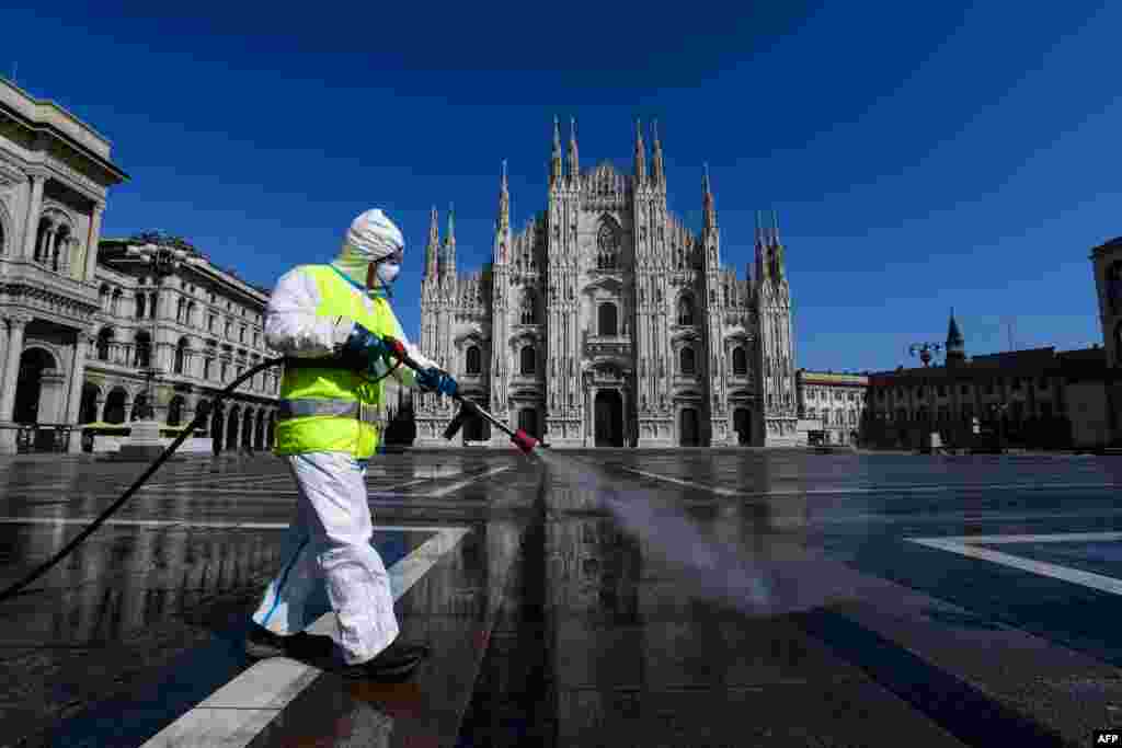 An employee sprays disinfectant on Piazza Duomo in Milan during Italy&#39;s lockdown aimed at curbing the spread of the COVID-19 infection.