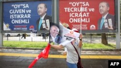 Seorang pendukung kandidat presiden Turki dari partai oposisi utama, Muharrem Ince dari Partai Rakyat Republik, melambaikan bendera saat berjalan melewati poster-poster kampanye petahana, Presiden Recep Tayyip Erdogan, dalam pawai pemilu di Ankara, 22 Juni 2018.