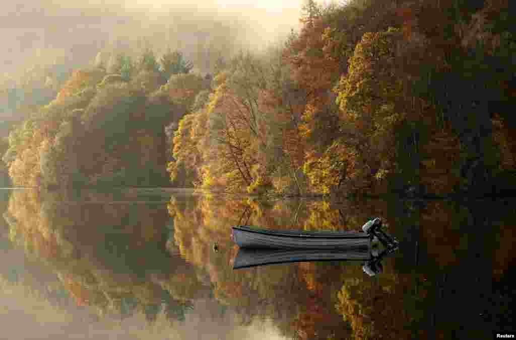 Autumn foliage is reflected on Loch Faskally in Pitlochry, Scotland.