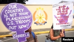 FILE - Protesters hold placards as they demonstrate against the ongoing negotiations between the U.S. and the Philippines in front of the military headquarters in Quezon city, metro Manila, Aug. 15, 2013.