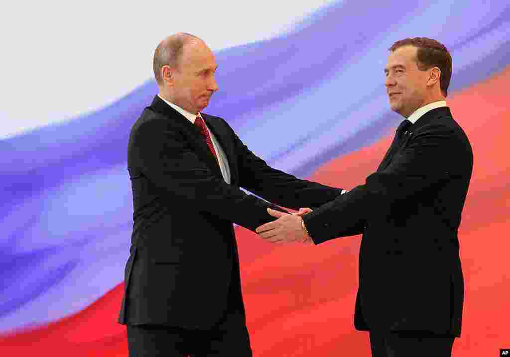 ປະທານາທິບໍດີ Vladimir Putin, ຊ້າຍ, ກັບອະດີດປະທານາທິບໍດີ Dmitry Medvedev ຈັບມືກັນ ໃນພິທີສາບານໂຕ. (AP)