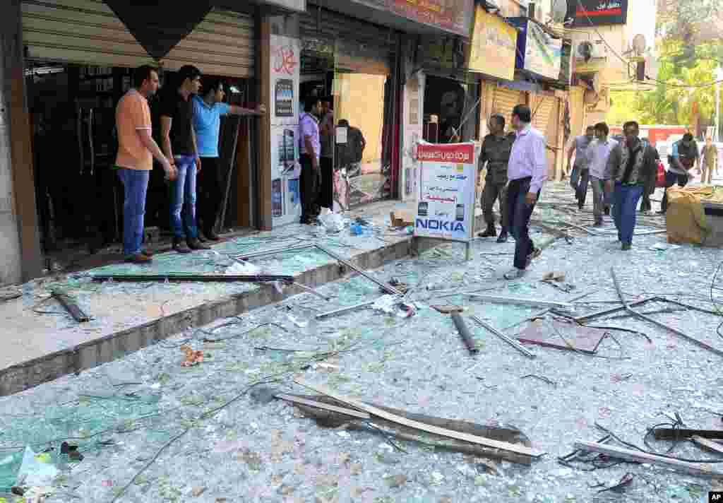 Syrian security officers, right, speak with shop owners at the scene of a powerful explosion that occurred in the central district of Marjeh, in Damascus, Syria, April 30, 2013. 