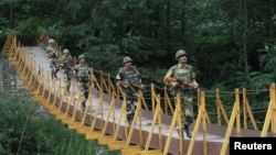 FILE - Indian Border Security Force soldiers patrol over a footbridge built over a stream near the Line of Control, a cease-fire line dividing Kashmir between India and Pakistan, at Sabjiyan sector of Poonch district, August 2013.