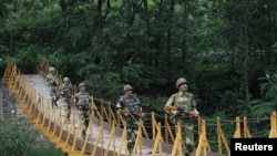 FILE - Indian Border Security Force soldiers patrol over a footbridge built over a stream near the Line of Control, a cease-fire line dividing Kashmir between India and Pakistan, at Sabjiyan sector of Poonch district.