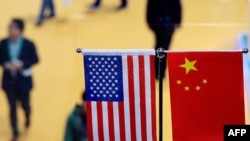 This file picture taken on November 6, 2018 shows a Chinese and US flag at a booth during the first China International Import Expo in Shanghai. - The US public's opinion of China has plummeted amid a surge in strategic and trade tensions in recent years