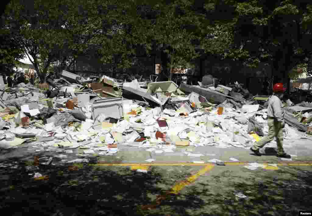 A worker walks past debris piled outside the headquarters of state-owned oil giant Pemex in Mexico City, January 31, 2013.