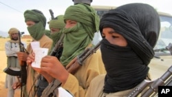 FILE - Young fighters display their Quranic studies notes for a journalist as their Islamist commanders look on, in Douentza, Mali.