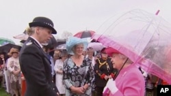 In an image made from pool video, Queen Elizabeth II speaks with Metropolitan Police Commander Lucy D'Orsi in the garden of Buckingham Palace in London, May 10, 2016. The queen was overheard on video describing Chinese officials as "very rude."