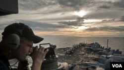 Seorang petugas pengawas pantai, Jacob Williams, menggunakan teleskop untuk mengamati kapal induk USS Carl Vinson (CVN 70) dan Carrier Strike Group (CSG) 1 mendekati Surigao Strait, FIlipina (Foto: dok).