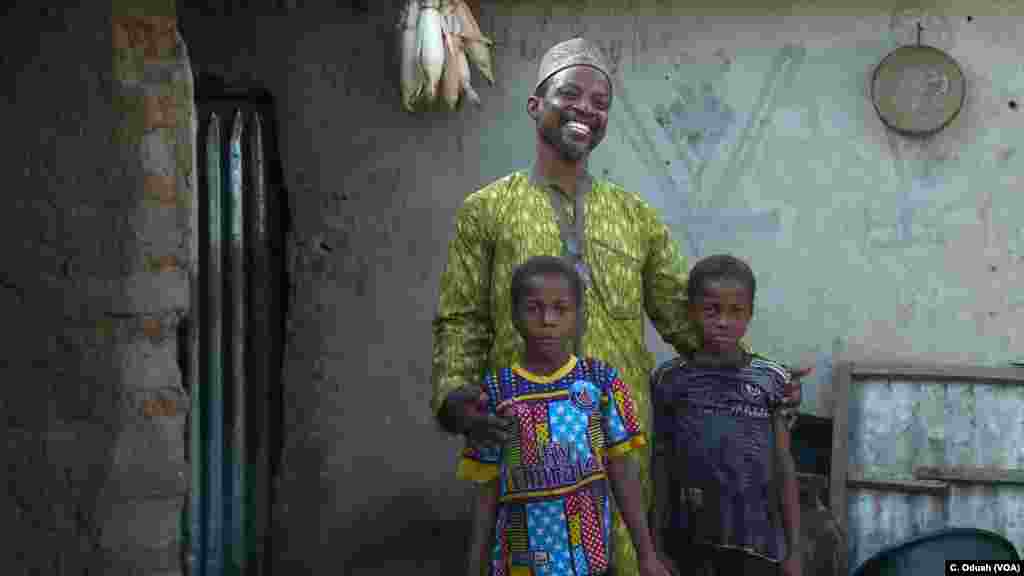 Steven Ajayi smiles with twin sisters Yauseh and Asana. The 10-year-old girls are the oldest set of twins living in Kutara village. Kutara was one of the first villages that ended ritual infanticide after Ajayi’s missionary work in the community.