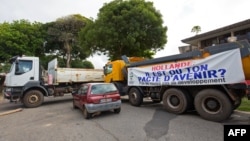 Trucks form a blockade in Cayenne on March 26, 2017, with a banner reading "Hollande (refering to French president Francois Hollande), where is your deal on the future ? No roads, no development". 