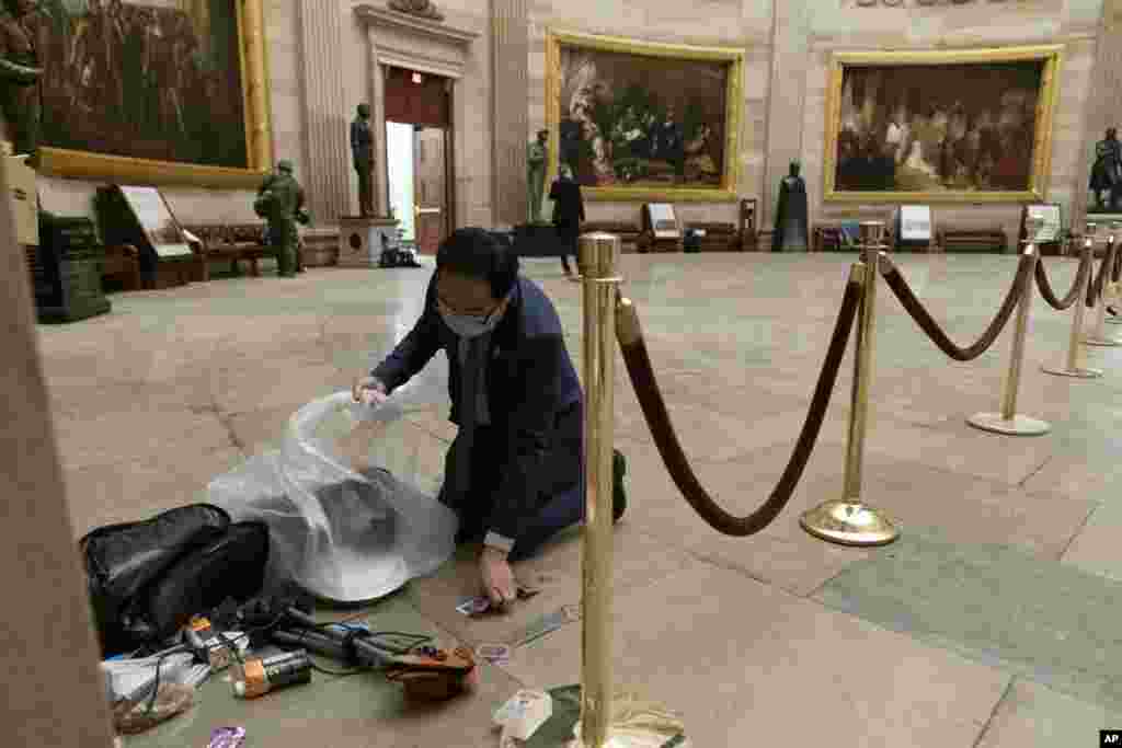 Lawmaker Andy Kim, a Democrat from New Jersey, cleans up damaged remains and personal belongings spread across the floor of the Rotunda after rioters stormed the Capitol Building on January 6, 2021, in Washington, D.C.
