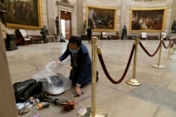 Rep. Andy Kim, D-N.J., cleans up debris and personal belongings strewn across the floor of the Rotunda in the early morning hours of Thursday, Jan. 7, 2021, after protesters stormed the Capitol in Washington, on Wednesday.