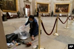 Rep. Andy Kim, D-N.J., cleans up debris and personal belongings strewn across the floor of the Rotunda in the early morning hours of Thursday, Jan. 7, 2021, after protesters stormed the Capitol in Washington, on Wednesday.