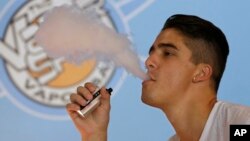 FILE - A smoker exhales vapor from an e-cigarette at the Vapor Spot, in Sacramento, California, in this July 7, 2015, photo.
