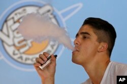 FILE - A smoker exhales vapor from an e-cigarette at the Vapor Spot, in Sacramento, California, in this July 7, 2015, photo.