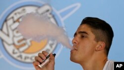 FILE - A smoker exhales vapor from an e-cigarette at the Vapor Spot, in Sacramento, California.