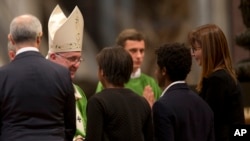 Pope Francis meets a family during a Mass in St. Peter's Basilica at the Vatican, Oct. 25, 2015. Pope Francis celebrated a final Mass to close out a historic meeting of bishops.