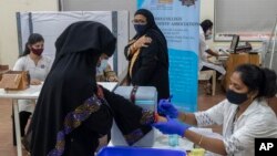 A woman hold her arm after receiving Covishield COVID-19 vaccine at a vaccination center in Mumbai, India, Monday, Nov. 29, 2021. (AP Photo/Rafiq Maqbool)