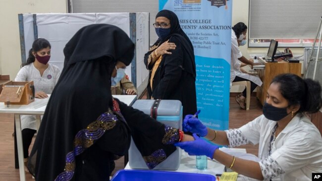 A woman hold her arm after receiving Covishield COVID-19 vaccine at a vaccination center in Mumbai, India, Monday, Nov. 29, 2021. (AP Photo/Rafiq Maqbool)