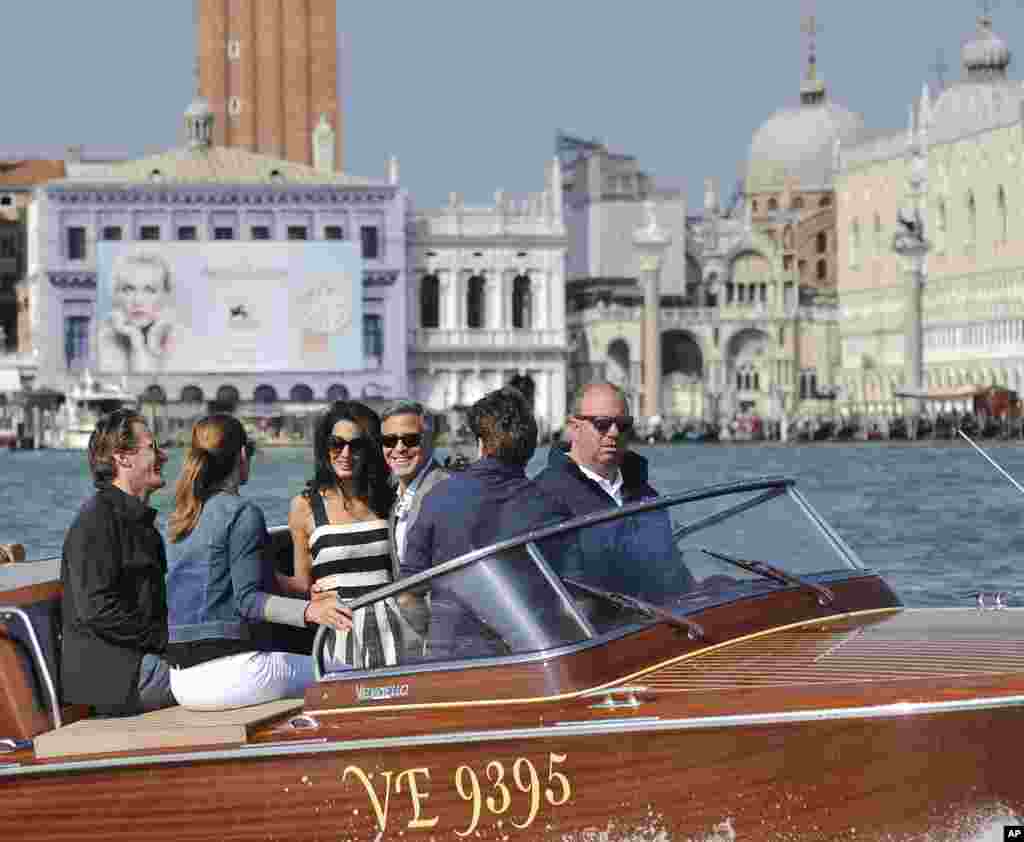 George Clooney, third right, his fiancee Amal Alamuddin, Cindy Crawford and her husband Rande Gerber cruise past St. Mark's Square as they arrive in Venice, Italy. Clooney and Alamuddin are expected to get married this weekend in Venice, one of the world's most romantic settings.