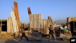 Afghan men pull their carts pass roadside timber stalls in Kabul, Afghanistan, Tuesday, June 21, 2011. (AP Photo/Gemunu Amarasinghe)