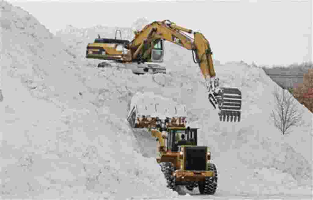 Workers use heavy equipment to create a mountain of snow collected from surrounding parking lots at Shoppers World in Framingham, Massachusets, USA, January 28, 2011.
