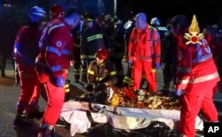 In this frame taken from video, rescuers assist injured people outside a nightclub in Corinaldo, central Italy, early Dec. 8, 2018.