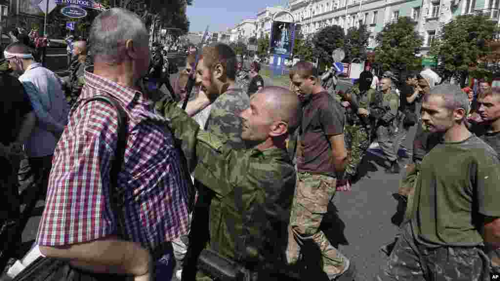 Pro-Russian rebel tries to stop a man who slaps a captured Ukrainian army prisoner they are escorting on central square in Donetsk, eastern Ukraine, Aug. 24, 2014. 