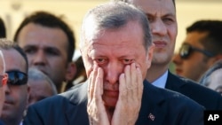 Turkish President Recep Tayyip Erdogan right, wipes his tears during the funeral of Mustafa Cambaz, Erol and Abdullah Olcak, killed Friday while protesting the attempted coup against Turkey's government, in Istanbul, July 17, 2016. 