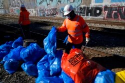 Para petugas membersihkan kardus-kardus dan barang-barang bekas lainnya di lokasi rel kereta api Union Pacific, Los Angeles, 20 Januari 2022. (AP)