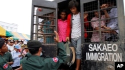 Cambodian migrant workers get off from a Thai truck upon their arrival from Thailand at Cambodia-Thai international border gate in Poipet, Cambodia, Tuesday, June 17, 2014. 
