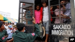 Cambodian migrant workers get off from a Thai truck upon their arrival from Thailand at Cambodia-Thai international border gate in Poipet, Cambodia, Tuesday, June 17, 2014.