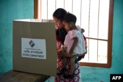 An Indian voter holds a child as she casts her ballot in the state assembly elections at a polling station in Diphu in the Karbi Anglong district some 215kms from Guwahati on April 4, 2016.