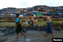 Rohingya refugees carry an old woman in a sling near Balukhali makeshift refugee camp in Cox's Bazar, Bangladesh, Sept. 13, 2017.