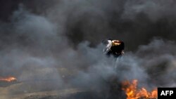 Un manifestant palestinien au milieu de pneus enflammés lors d'affrontements avec les forces israéliennes à la frontière entre Gaza et Israël, le 20 avril 2018.