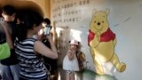 A child poses for photos near a mural depicting Winnie the Pooh in Shanghai, China, Aug. 8, 2018. 