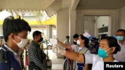 Migrant workers from Myanmar get their temperatures taken by healthcare workers at the Myawaddy border office after passing through border gate at Myawaddy, Myanmar, after leaving Thailand due to the coronavirus disease (COVID-19) outbreak, March 24, 2020