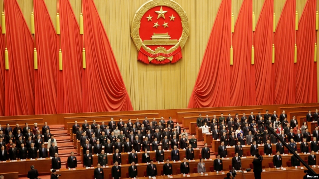 资料照：在北京人大会堂参加全国人大会议的中国官员起立唱国歌。（2019年3月15日）