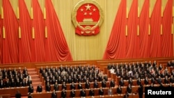 资料照：在北京人大会堂参加全国人大会议的中国官员起立唱国歌。（2019年3月15日）