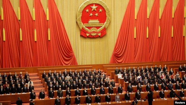 资料照:在北京人大会堂参加全国人大会议的中国官员起立唱国歌。(2019年3月15日)