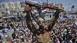 یک افسر یمنی در حالی که همراه دیگر افسران ارتش به جمع مخالفان رییس جمهوری یمن پیوسته است، اسلحه خود را بالا می گیرد. ۲۱ مارس ۲۰۱۱