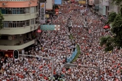 Protesters march along a downtown street against the proposed amendments to an extradition law in Hong Kong Sunday, June 9, 2019