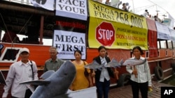 FILE - Cambodian non-governmental organization (NGOs) activists hold a cut-out of Mekong dolphin, left, and cut-out of other species during a protest against a proposed Don Sahong dam, in Phnom Penh, Cambodia.