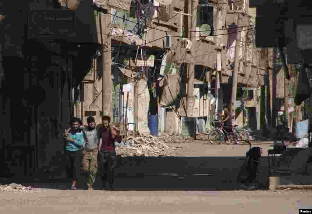 Members of the Free Syrian Army help a wounded fellow fighter in Deir al-Zor, May 14, 2013.