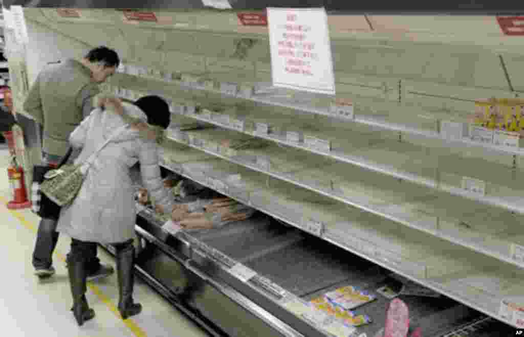 People shop for food from an almost empty shelf at a store in Tokyo March 15, 2011, after an earthquake and tsunami hit northern Japan. REUTERS/Kyodo (JAPAN - Tags: DISASTER BUSINESS) FOR EDITORIAL USE ONLY. NOT FOR SALE FOR MARKETING OR ADVERTISING CAMPA