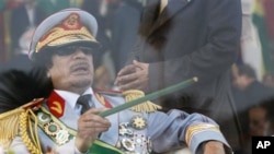 Libyan leader Moammar Gadhafi gestures with a green cane as he takes his seat behind bulletproof glass for a military parade in Green Square, Tripoli, Libya, September 1, 2009 (file photo)
