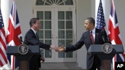 British Prime Minister David Cameron and President Barack Obama reach to shake hands during their joint news conference in the Rose Garden of the White House in Washington, March 14, 2012. 