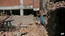 A Nepalese woman collects bricks from a destroyed building in Bhaktapur, Nepal, April 24, 2017. Nepal's government has been criticized for moving slowly in dispersing funds that would allow people to rebuild.